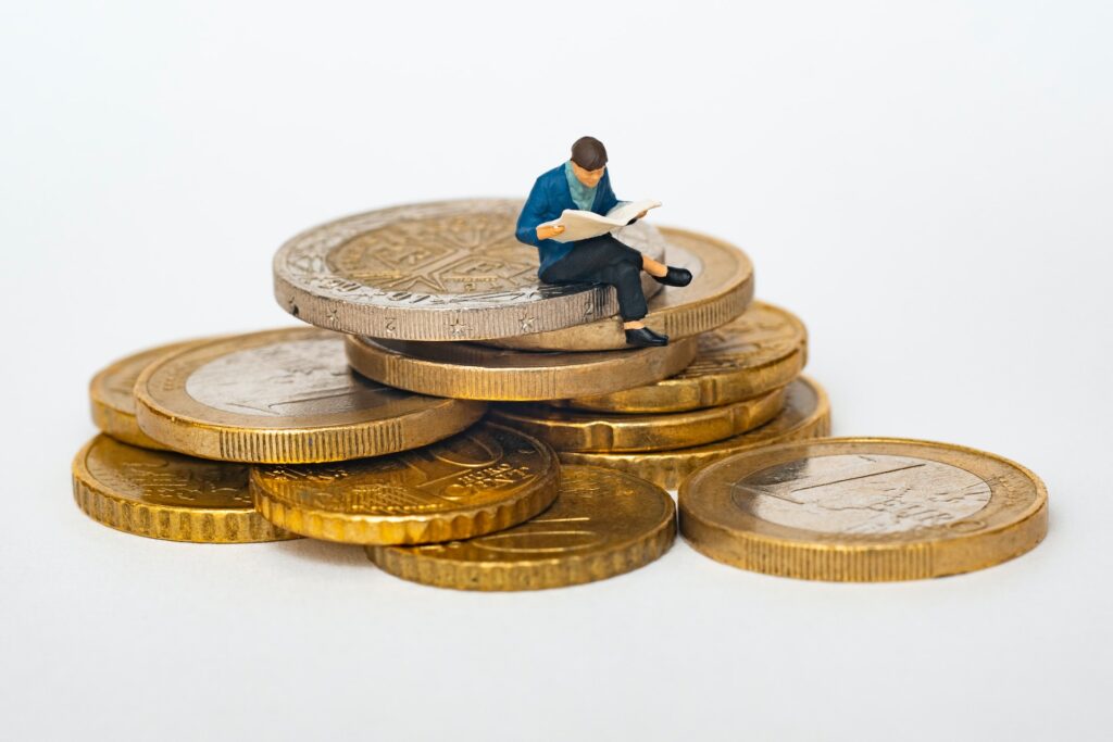 a man sitting on big coins and reading something